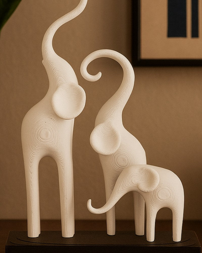 Minimalistische olifantensculptuur met drie gestileerde figuren op een donkere sokkel, witte achtergrond, close-up
