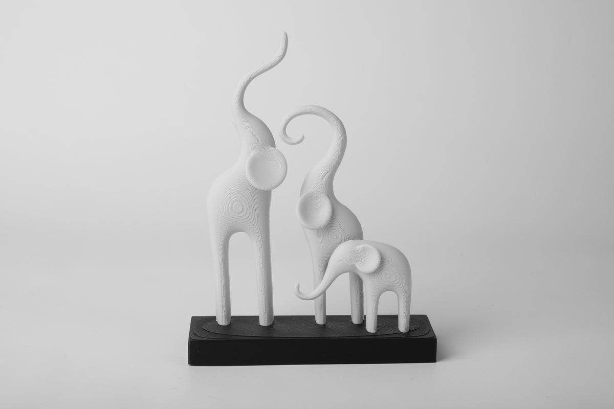 Minimalistische sculptuur van een olifantenfamilie op een lichte houten plank met neutrale Scandinavische decoratie