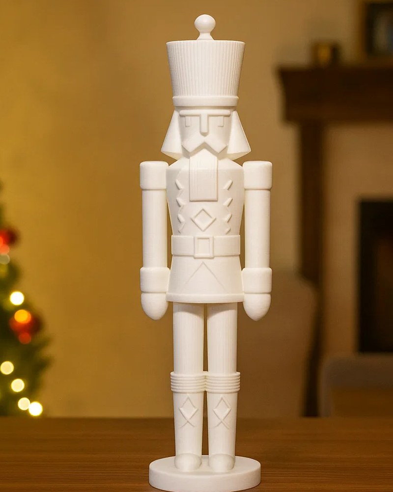 Minimalistische notenkrakersculptuur in matwit op een witte plank, vooraanzicht
