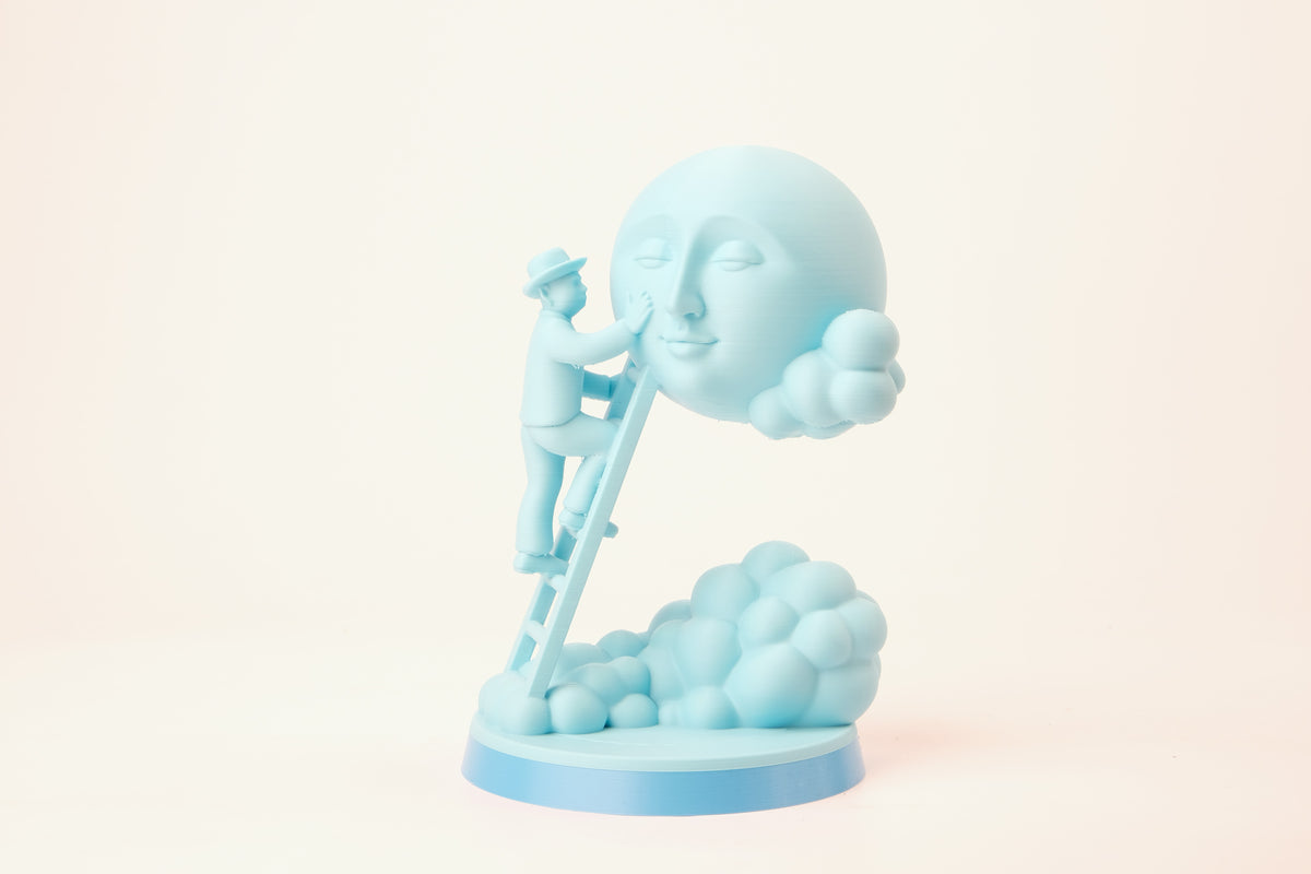 Moon Caretaker-sculptuur op een minimalistische plank tussen boeken en een plantje