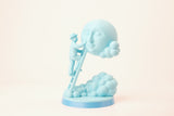 Moon Caretaker-sculptuur op een minimalistische plank tussen boeken en een plantje