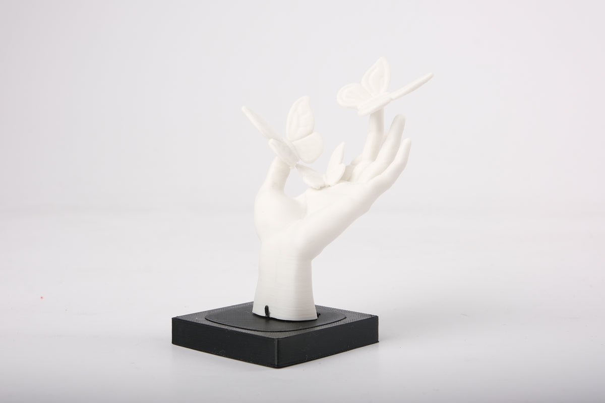 Hand met vlinders als beeld op een minimalistische houten plank bij een kleine keramische vaas