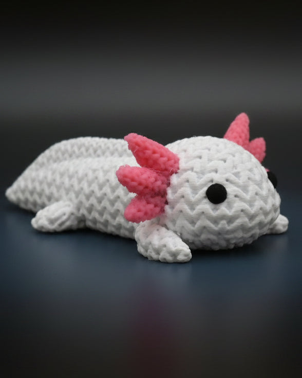 Kleine gebreide axolotl op een houten plank bij boeken en een plant in Scandinavisch interieur