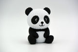 Gebreid figuurtje van een panda op een houten plank naast planten en neutrale woondecoratie