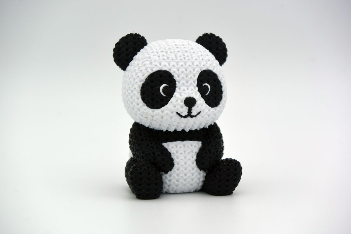 Gebreid figuurtje van een panda op een houten plank naast planten en neutrale woondecoratie