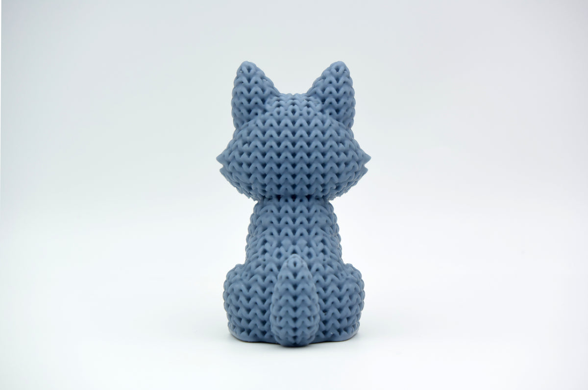 Close-up van een gebreid wolvenfiguurtje met gehaakte textuur in warm grijs, ca. 10 cm hoog