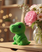 Gebreide T-Rex op houten plank naast boeken en kleine plant in rustig Scandinavisch interieur