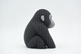 Gebreid figuurtje van een gorilla op een houten plank naast boeken en een plantje