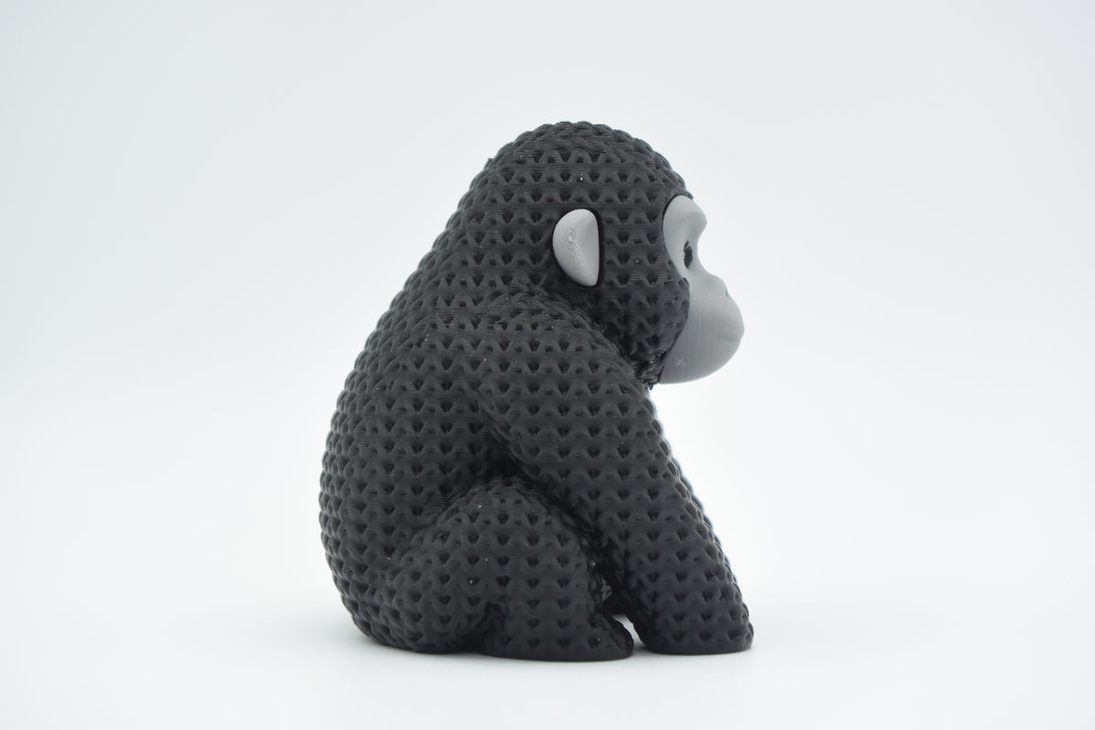 Gebreid figuurtje van een gorilla op een houten plank naast boeken en een plantje