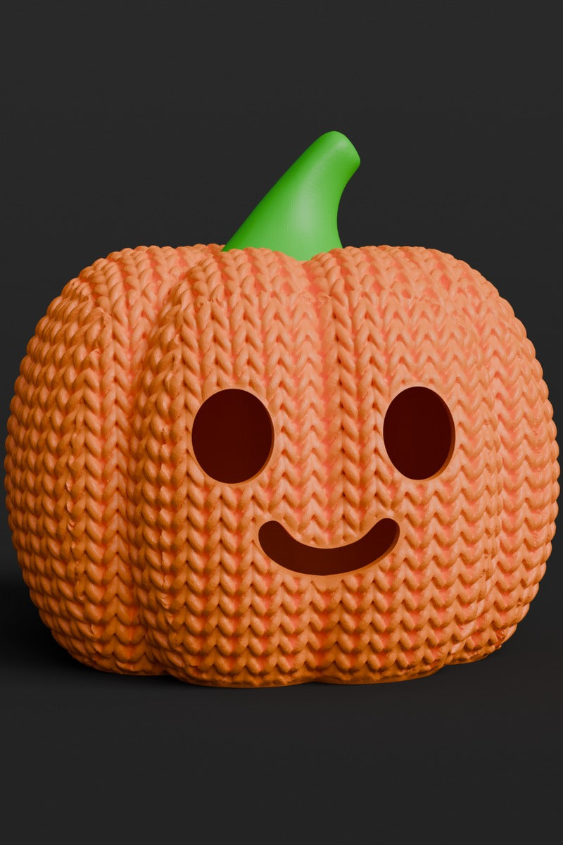 Close-up van een gebreide halloweenpompoen met pompoengezicht en zachte oranje textuur