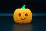 Detail van de structuur van een gebreide halloweenpompoen met geweven patroon en uitgesneden gezicht