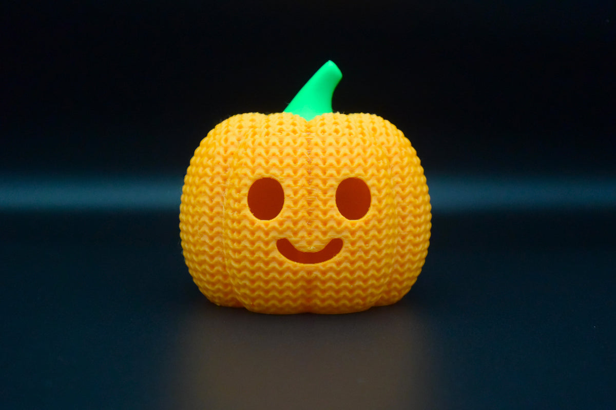 Detail van de structuur van een gebreide halloweenpompoen met geweven patroon en uitgesneden gezicht