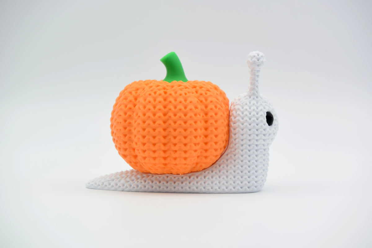 Gebreide pompoenslak als halloweendecoratie op een houten plank met gedroogde herfstbladeren en kaarsjes