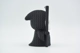 Klein gebreid halloweenfiguurtje van Magere Hein op een donkere houten plank bij herfstbladeren