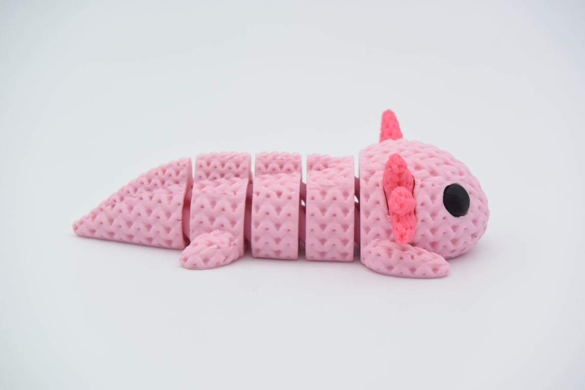 Gebreide flexi-axolotl op houten plank naast kleine plant