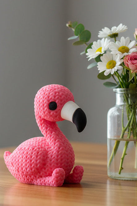 Close-up van een roze gebreid flamingofiguurtje met gehaakte look, rechtop staand