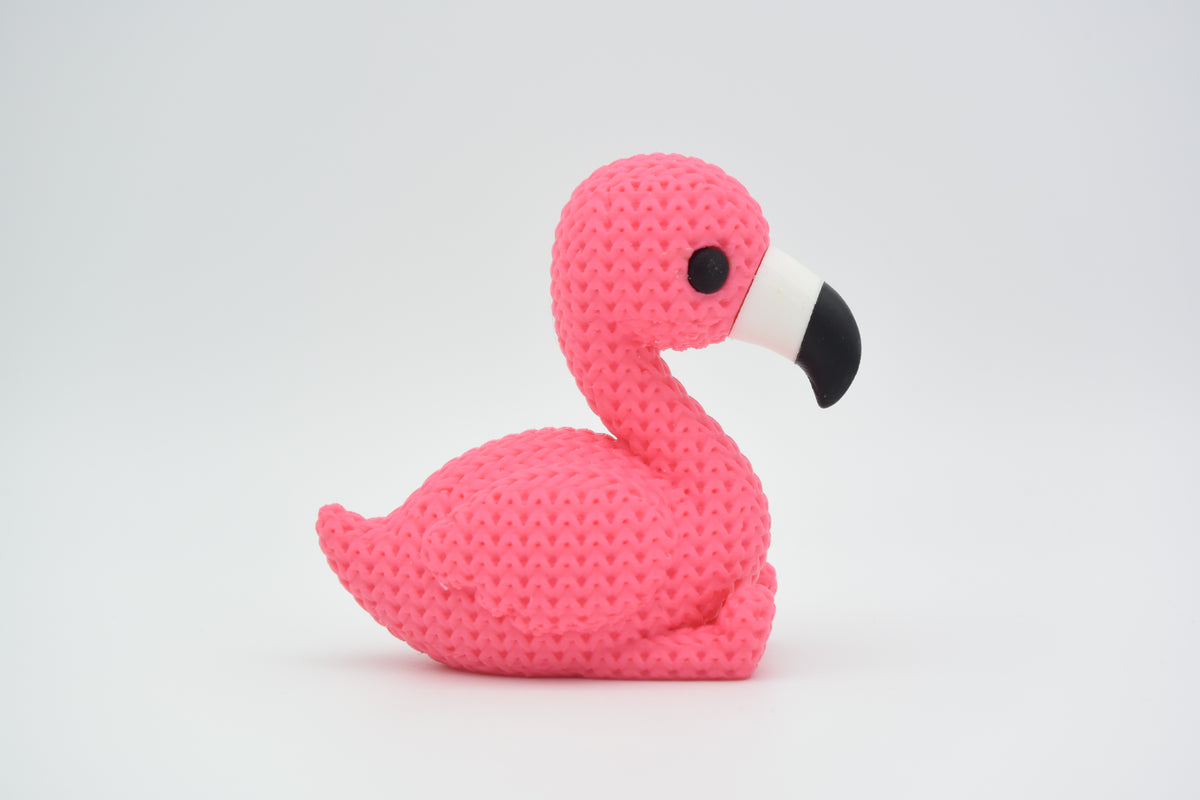 Gebreid figuurtje van een flamingo op een houten plank naast een plantje en neutrale woondecoratie
