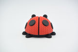 Close-up van een gebreid lieveheersbeestje in rood en zwart met gehaakte look op een wit vlak