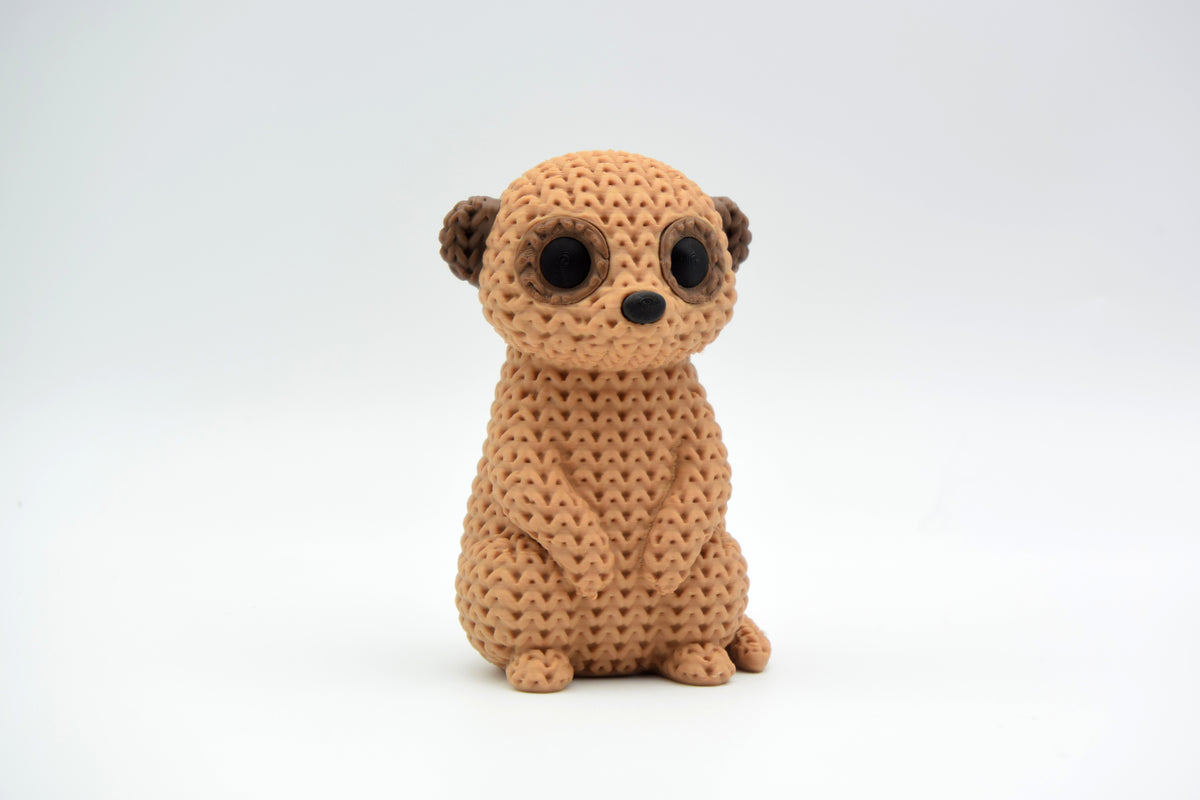 Close-up van een gebreid stokstaartjesfiguurtje met gehaakte textuur, rechtop staand op witte achtergrond