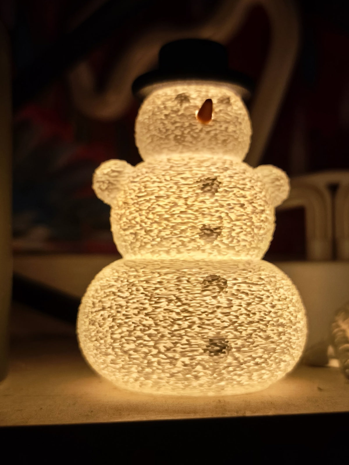 Sneeuwpop met hoed en neus over een led-theelichtje